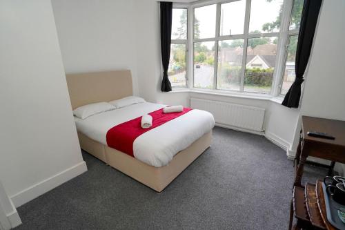 a bedroom with a bed and two windows at Birchwood-Lodge in Horley
