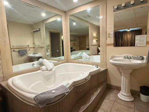 a bathroom with a tub and a sink and a mirror at Hotel Motel La Marquise in Sherbrooke
