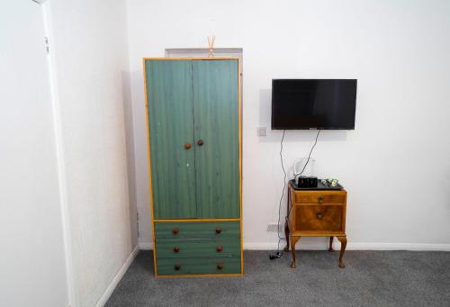 a green cabinet next to a tv and a dresser at Birchwood-Lodge in Horley