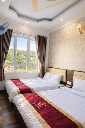 two beds in a bedroom with a window at Bình Dương Đà Lạt Hotel in Da Lat