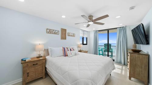 a white bedroom with a bed and a balcony at Steps to the beach and amazing views! in Panama City Beach