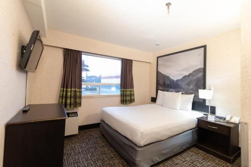 a hotel room with a bed and a large window at Super 8 by Wyndham Prince George in Prince George