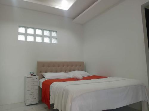 a bedroom with a bed with a red and white blanket at MANEL Guest House - Donsol, Philippines in Donsol