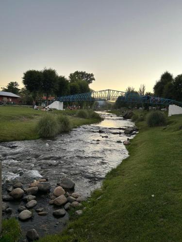 a river with rocks and a bridge in the background at El Atardecer in Trapiche