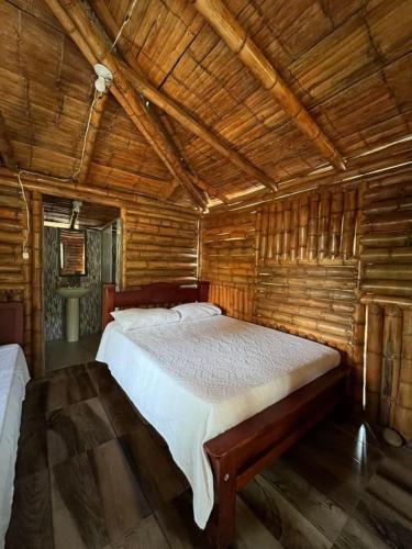 a bedroom with a bed in a wooden cabin at Cabañas Aires de mi campo in Paicol