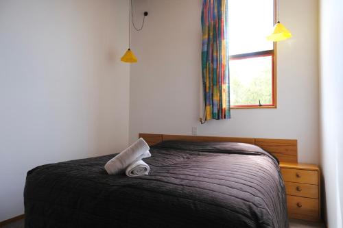 a bedroom with a bed with two rolled towels on it at Forest Trail Lodge in Hanmer Springs