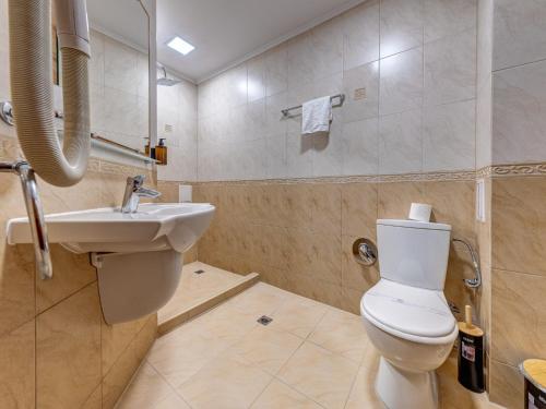 a bathroom with a white toilet and a sink at Хотел Елит Релакс in Devin