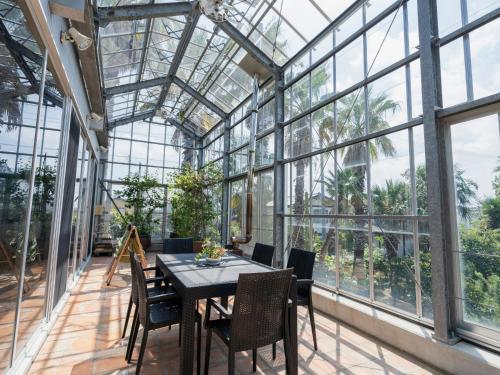 a dining room with a table and chairs in a glass house at Palm Villa - Vacation STAY 12202 in Takamatsu