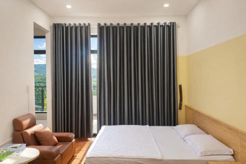 a bedroom with a bed and a chair and a window at Khôi Đại Hotel - gần sân bay Buôn Ma Thuột, near Buon Ma Thuot Airport in Buon Ma Thuot