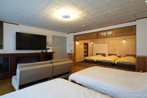 a hotel room with two beds and a flat screen tv at Fujiyama Stay Sengen West in Fujinomiya