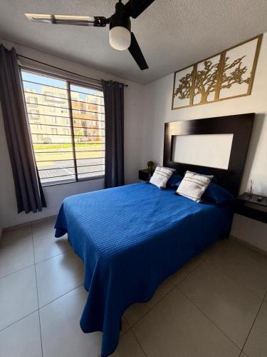 a bedroom with a blue bed with a ceiling fan at Hermoso y Comfortable Departamento 15 min del Aeropuerto in Guadalajara