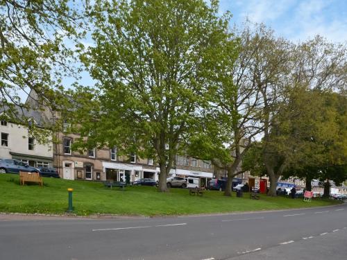 a park with benches and trees on the side of a street at The Malt House in Rothbury