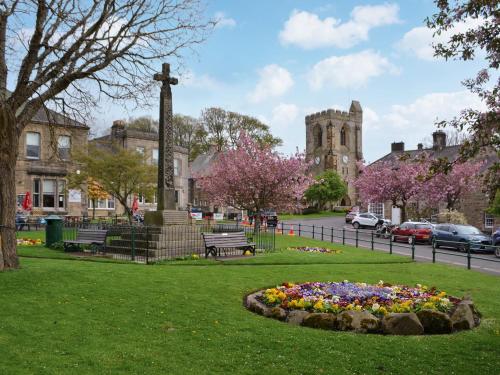 a park with a cross and a flower bed in the grass at The Malt House in Rothbury