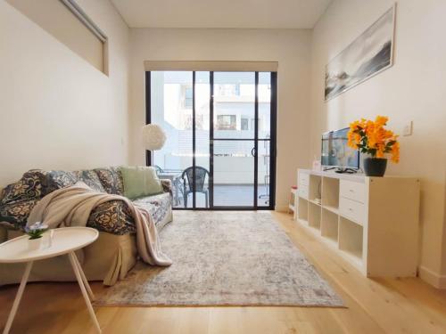 a living room with a couch and a tv at Premium location one bedroom APT with secure car parking - 5 mins Train, Shops in Eastwood