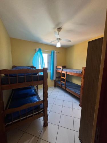 a room with three bunk beds and a ceiling fan at Apto Verde Água in Mongaguá