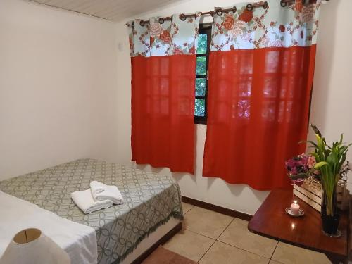 a small room with a bed and red curtains at Pousada Jacu Acu in Petrópolis