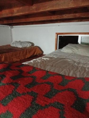 a bedroom with two beds and a red carpet at Loft in El Tabo