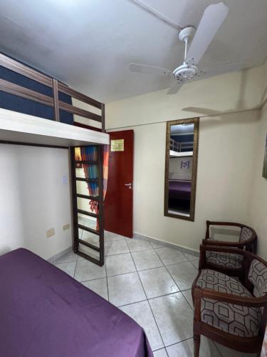 a bedroom with a bunk bed and a chair at Apto Lilas in Mongaguá