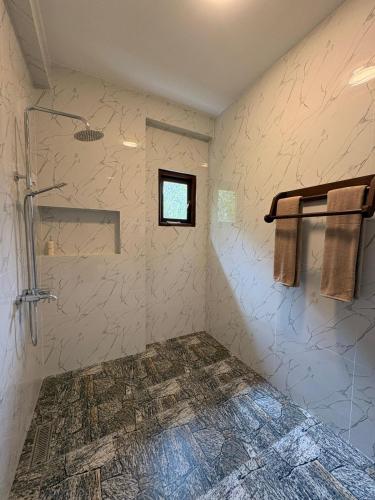 a bathroom with a shower and a window at Liora Cottage Ella in Ella