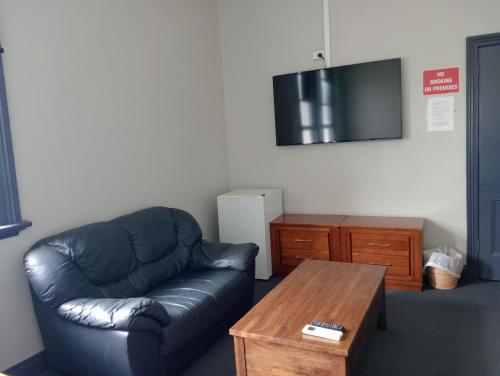 a living room with a leather couch and a coffee table at Australia Hotel Fremantle in Fremantle