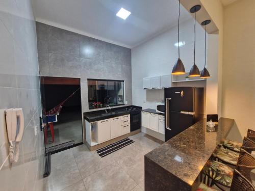 a kitchen with a black refrigerator and a counter at Casa Alves Próx Hospital do Amor Com Suíte e Ar in Barretos