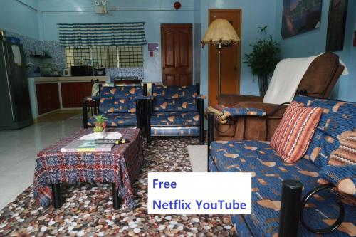 a living room with chairs and a table with a sign free netflix youtube at YOO C Apartment - Free Netflix YouTube in Dumaguete