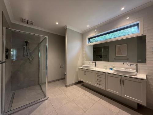 a bathroom with two sinks and a shower and a mirror at The Grand Oasis in Donvale