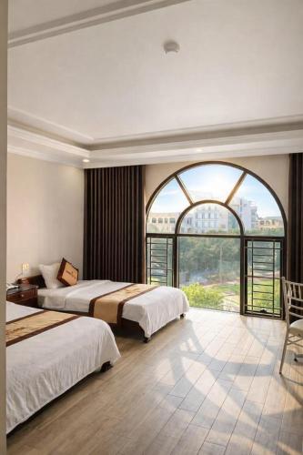 a bedroom with two beds and a large window at Asean Hotel in Hải Dương
