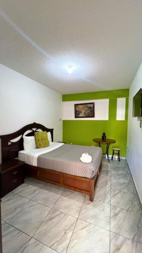 a bedroom with a large bed with green walls at Hostal Mago in Tlaxcala de Xicohténcatl