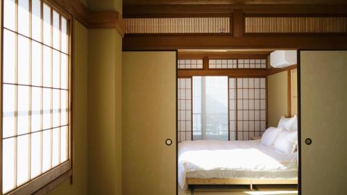 a bedroom with a bed and two windows at New Open T-House Kyoto-2 豪華鄰近二條城天然材質檜木清香帶露天風呂-放鬆的京都生活 in Kyoto