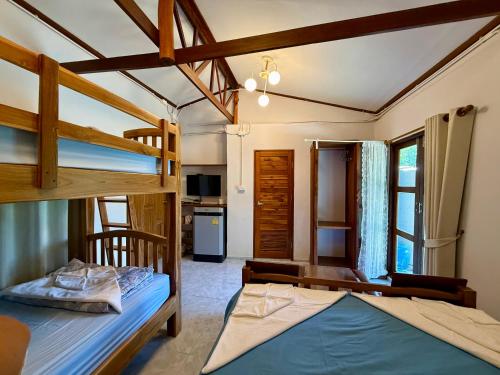 a bedroom with two bunk beds and a kitchen at Baan Chan Lay Koh Chang in Ko Chang