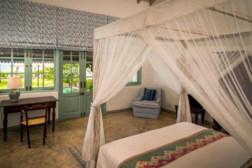 a bedroom with a canopy bed and a desk at Samudra Beach Villa in Habaraduwa Central