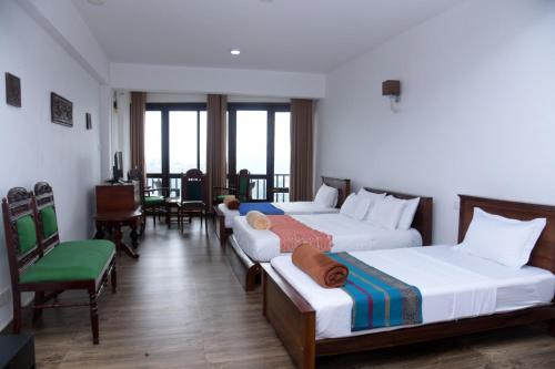 a hotel room with three beds and a balcony at Lawan One Kandy in Kandy