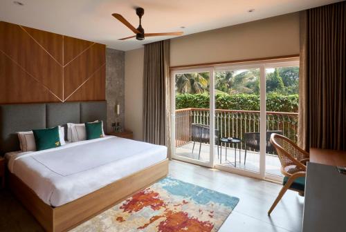 a bedroom with a bed and a balcony at The Passport Hotel in Assagao