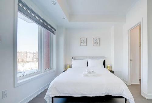 a white bedroom with a large bed and a window at Downsview Park Luxury Townhome near Yorkdale Transit in Toronto