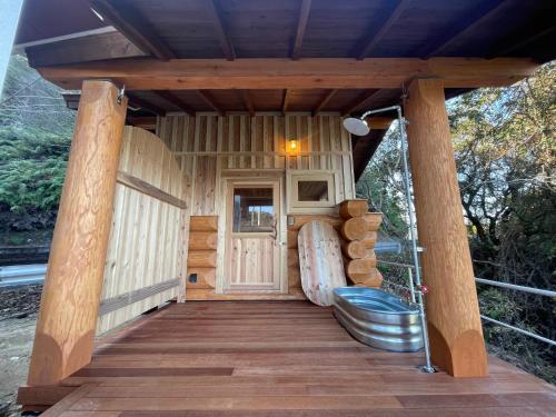 a wooden cabin with a door and a wooden deck at 椿ハウス 海の見えるサウナ付き貸切別荘 in Anan