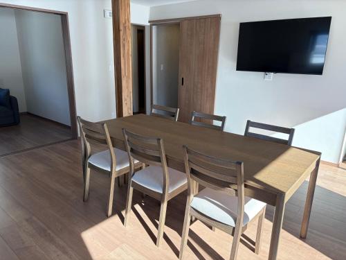 a dining room table with chairs and a television on a wall at あづまや野沢温泉 in Nozawa Onsen