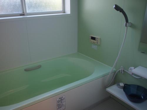 a bathroom with a bath tub with a hose at ゲストハウス有無 in Mihama