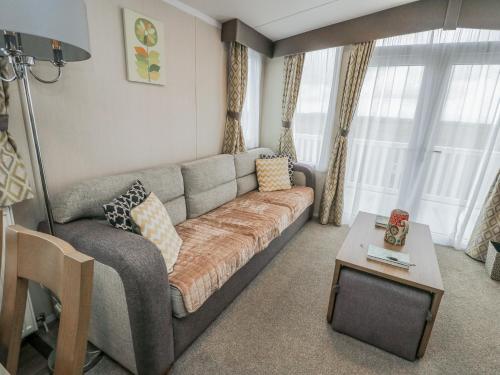 a living room with a couch and a table at Trewan Chalet in Holyhead