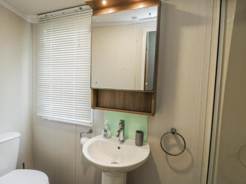 a bathroom with a sink and a mirror and a toilet at Trewan Chalet in Holyhead