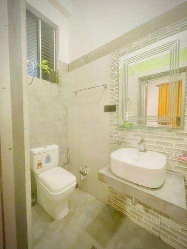 a bathroom with a white toilet and a sink at Delmar Homestay in Dickwella