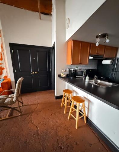 a kitchen with a counter and two stools in it at 420 Friendly BOHO Loft Downtown KING suite FREE parking in Detroit
