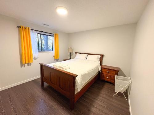 a bedroom with a bed and a window with yellow curtains at Vancouver UBC 3BD Garden Suite in Vancouver