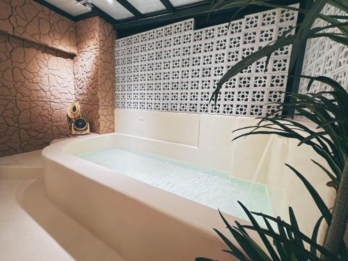 a bath tub in a bathroom with a plant at 禾夏民宿Her Shot Inn in Hengchun South Gate
