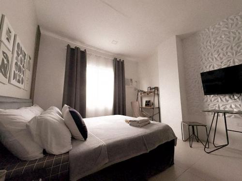 a bedroom with a bed with white sheets and a window at BES Building in Dasmariñas