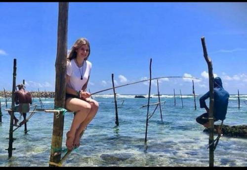 a woman sitting on a pole in the water at Happy Corner Ahangama in Midigama West