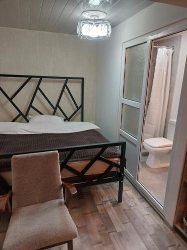 a bedroom with a bed and a chair and a toilet at Boutique hotel in Poti