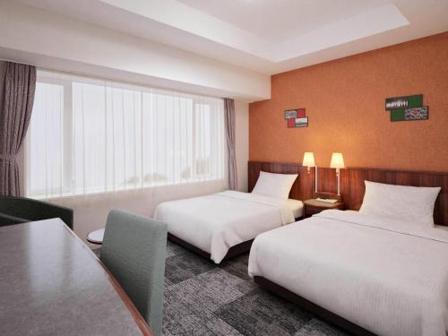 a hotel room with two beds and a table at Comfort Hotel Toyokawa in Toyokawa