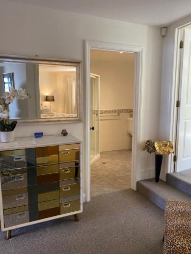 a room with a dresser with a mirror and a bathroom at Maison Blue - Chic Garden Apartment - Pet Friendly in Napier
