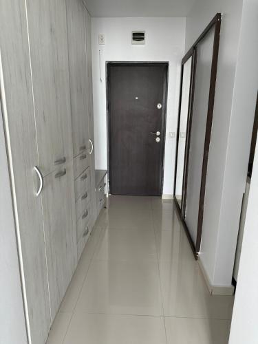 a hallway with a black door and a hallway with white floors at Apartment Saturn in Galaţi